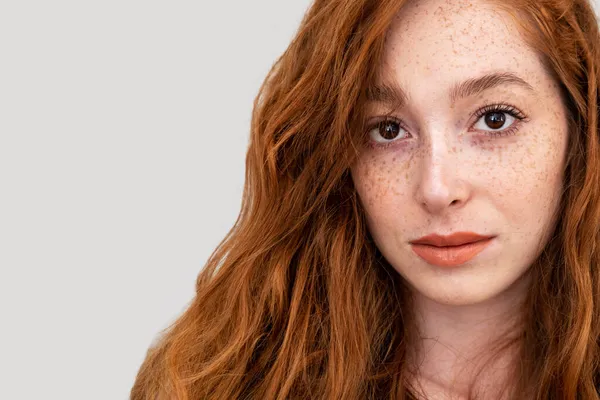 Faccia con lentiggini di una bella donna con capelli rossi e labbra isolate su sfondo grigio — Foto Stock