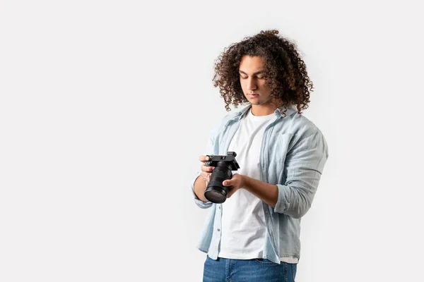 곱슬머리의 젊은 남자 가손에 카메라를 들고 있다. 호비와 사진 개념. — 스톡 사진