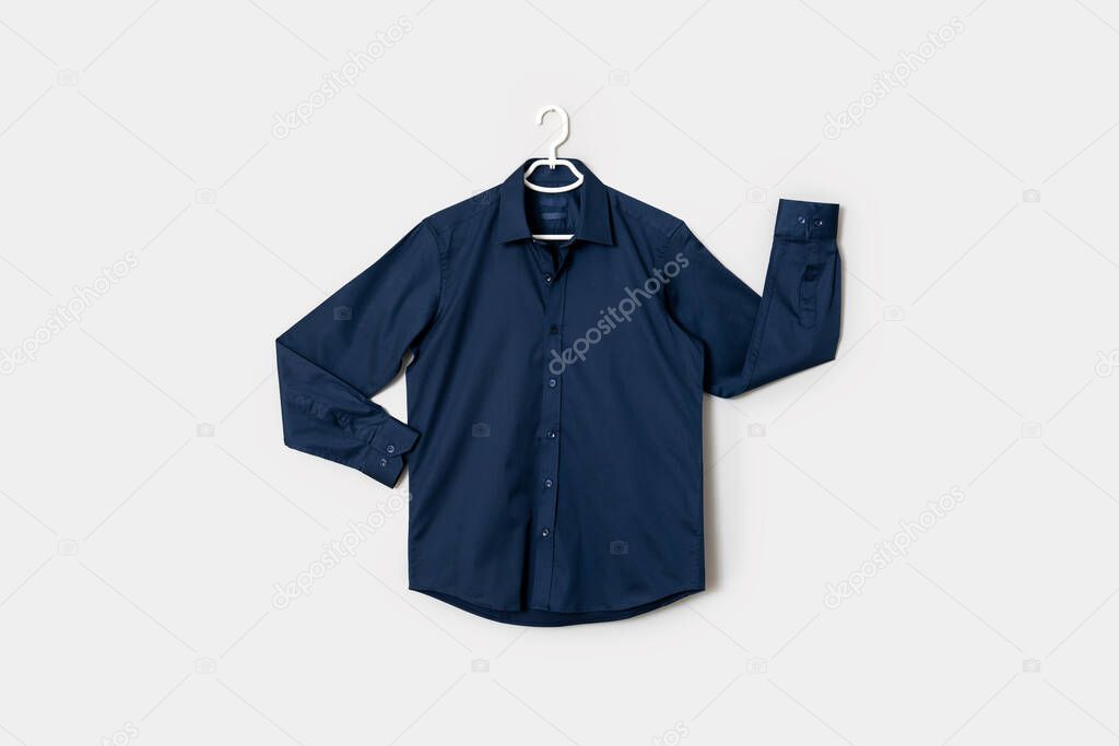 The front view of a dark blue colored button down shirt on a shirt hanger, isolated on white background. High quality photo