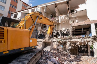 Ağır bir endüstriyel iş makinesi, kazıcı terk edilmiş eski bir binayı yok ediyor. Yüksek kalite fotoğraf