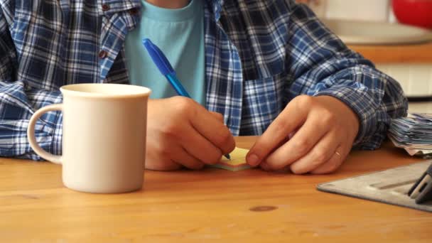 Hombre haciendo notas mientras está sentado en la cocina en la mesa — Vídeos de Stock