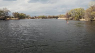 İnsansız hava aracı nehir yatağı boyunca ilerliyor. Kayıklı bir adamın yüzdüğü yerde.
