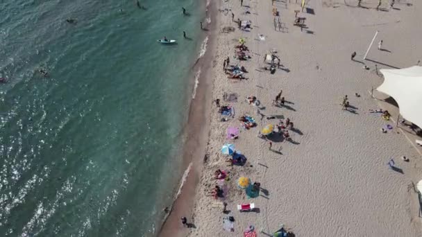 Беспилотник движется по пляжу у моря со многими людьми. — стоковое видео