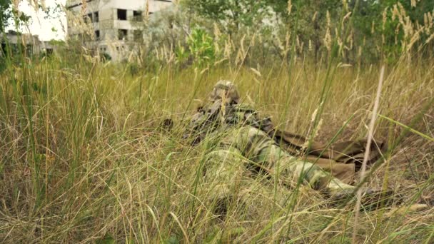 Солдат целится из снайперской винтовки, лежащей в засаде — стоковое видео