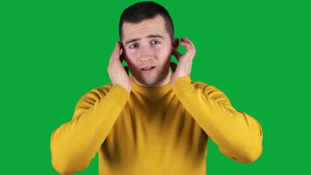 Hombre cubriéndose las orejas con las manos en una pantalla verde — Vídeos de Stock