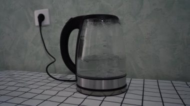 Elektrik kaynayan su ısıtıcısı masanın üzerinde duruyor.