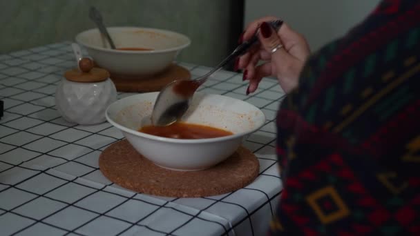 Девушка ест борщ, сидя за столом на кухне — стоковое видео