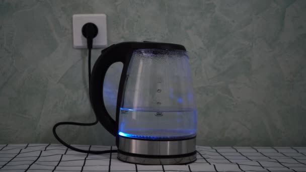 Стеклянный чайник кипит, стоя на столе — стоковое видео