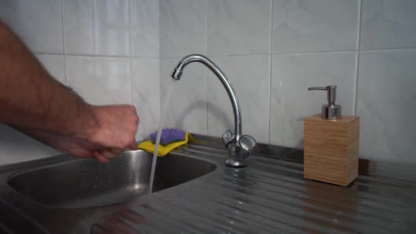 Ένας άντρας πλένει τα χέρια του κάτω από τη βρύση στην κουζίνα. — Αρχείο Βίντεο