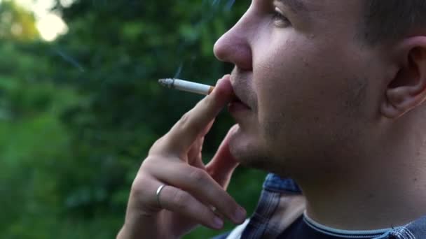 Чоловік курить цигарку, стоячи на вулиці — стокове відео