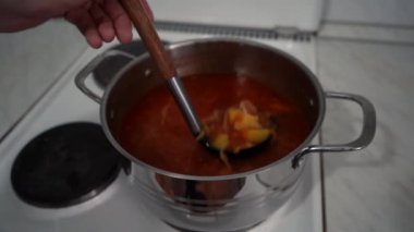 Bir tencerede pancar çorbası karıştıran adam.