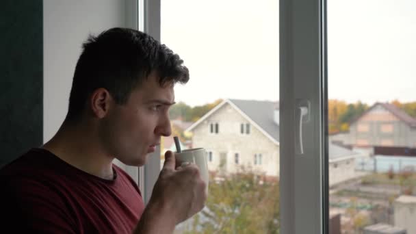Mężczyzna pijący kawę wczesnym rankiem stojący przy oknie — Wideo stockowe