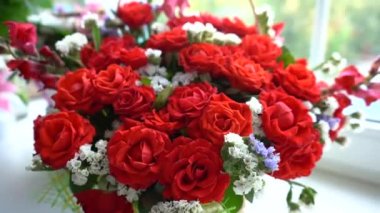 Vazonun pencere eşiğinde duran kırmızı gül buketi.