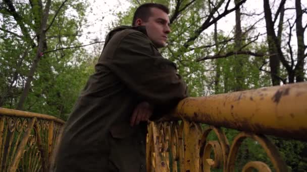 Грустный молодой человек с проблемами на мосту у реки, крупным планом. — стоковое видео