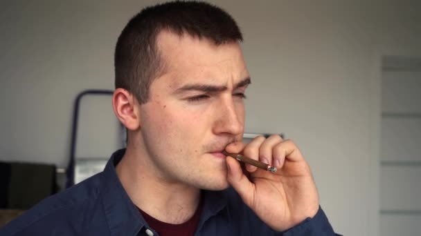 Hombre soplos en el cigarrillo de pie delante de la ventana — Vídeo de stock