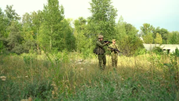 Dva vojáci v maskování se zbraněmi procházejí lesním prostorem — Stock video
