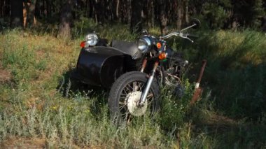 Eski Sovyet motosikleti çimlerin üzerinde duruyor.