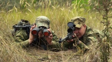 Silahlı bir keskin nişancı çalılıklarda pusuda bekliyor.