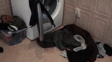 Bir adam kirli çamaşırları çamaşır makinesine atar..