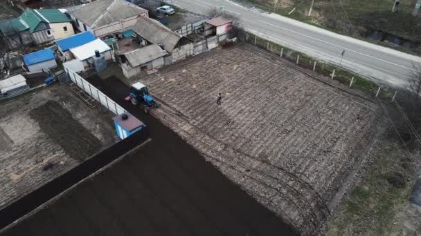 Голубой трактор вспахивает землю для сбора урожая — стоковое видео