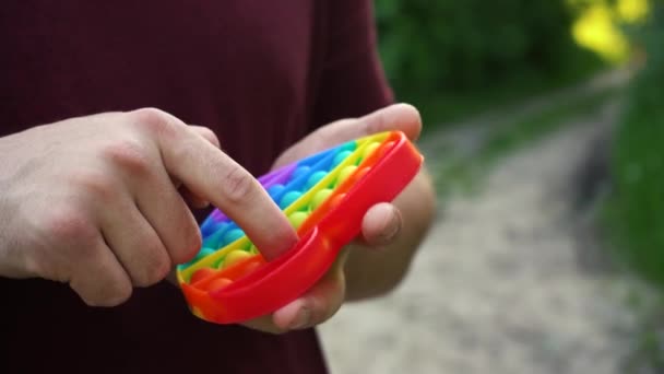 Человек играет с игрушкой поп-это просто ямочки сидя в парке — стоковое видео