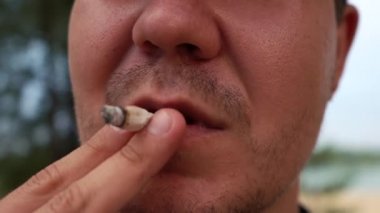Erkek sigarayı yakın plan çekimde tüttürür. 4k görüntü