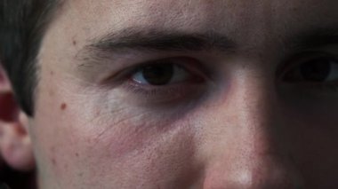 Gözlüklü adam kameraya yakından bakıyor.