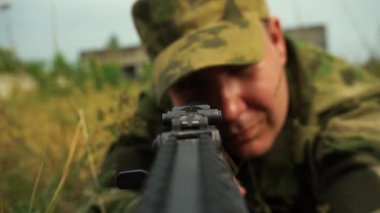 Erkek asker pusuda beklerken makineli tüfekle nişan alıyor.