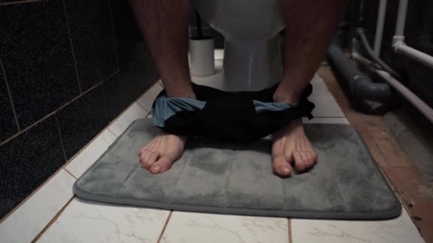 Muž si sundá kalhotky a sedí na záchodě — Stock video