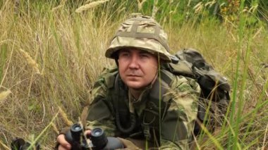 asker pusuda beklerken dürbünle bakıyor.