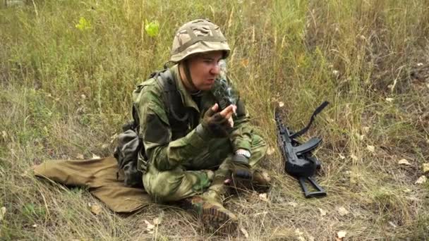 Soldado em camuflagem senta-se no chão e fuma — Vídeo de Stock