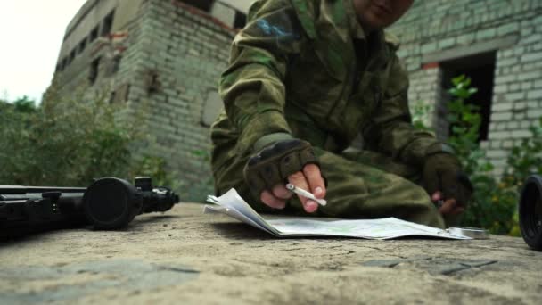 A military man examines a map of the area and smokes a cigarette — Stock Video