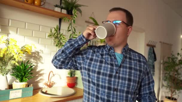 Muž pije čaj dívat se z okna, zatímco v kuchyni — Stock video