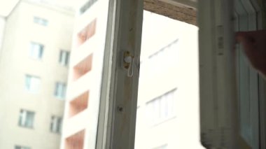 Bir adam bir dairenin penceresini açar.