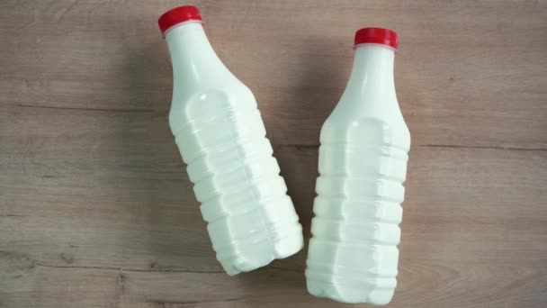 Dos botellas de leche sobre una mesa de madera — Vídeo de stock