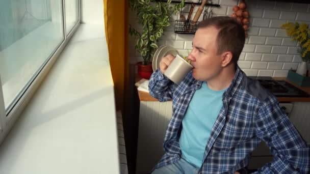 Muž pije čaj ráno, dívá se z okna v kuchyni — Stock video