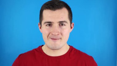 Erkek, mavi arka planda şaşkınlık ve şok hissi verir..