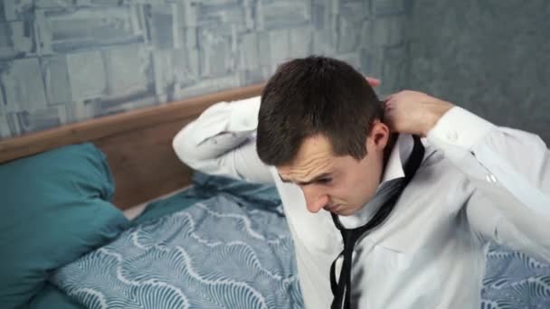 Молодой кавказский мужчина надевает черный галстук на белую рубашку. — стоковое видео