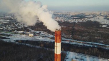 puffs of smoke come out of a tall chimney. 4k drone footage