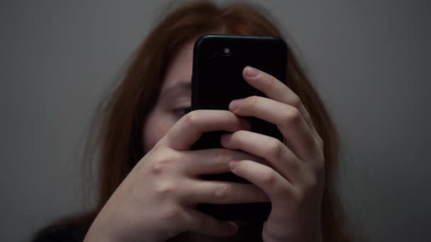 Mädchen benutzt das Telefon, um ihr Gesicht vor der Kamera zu verdecken — Stockvideo