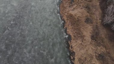frozen lake near the sandy shore. 4k aerial footage