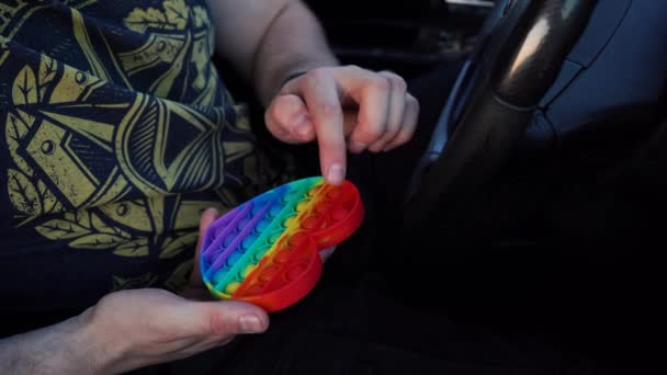 Мужчина играет в радугу, сидя в машине — стоковое видео