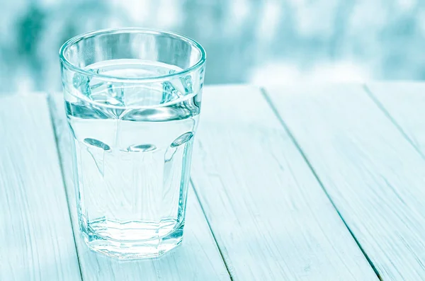 A glass with clean clear water. Glass of water with half full water on the table, concept of positive and negative thinking