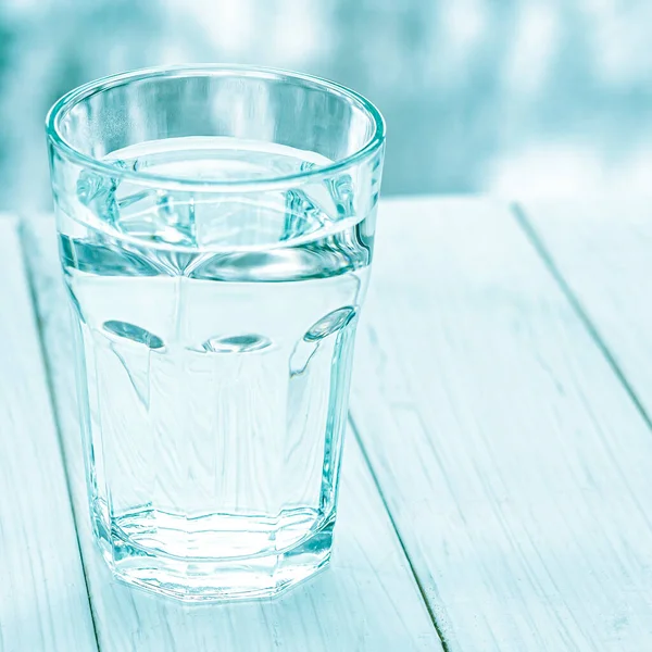 A glass with clean clear water. Glass of water with half full water on the table, concept of positive and negative thinking