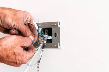 Yaşlı bir adamın elleri, beyaz bir duvara bir roset asıyor. Dairenin tamiri. İnternet