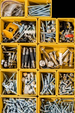 Küçük inşaat eşyalarıyla dolu sarı bir çanta. Vidalar, somunlar, civatalar, çiviler ve diğer aletleri atölyede bulunan inşaatçılarla dolu birçok depo kompartımanı. Düzenli ve düzenli.