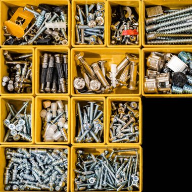 Küçük inşaat eşyalarıyla dolu sarı bir çanta. Vidalar, somunlar, civatalar, çiviler ve diğer aletleri atölyede bulunan inşaatçılarla dolu birçok depo kompartımanı. Düzenli ve düzenli.