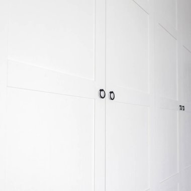 Beyaz, eski bir gardırop. Taçlı pervazlar. Ahşap raflar, çekmeceler.