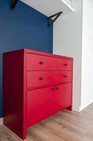 Cômoda vermelha em um interior escandinavo. Um armário de madeira vermelho com alças pretas está em um apartamento — Fotografia de Stock