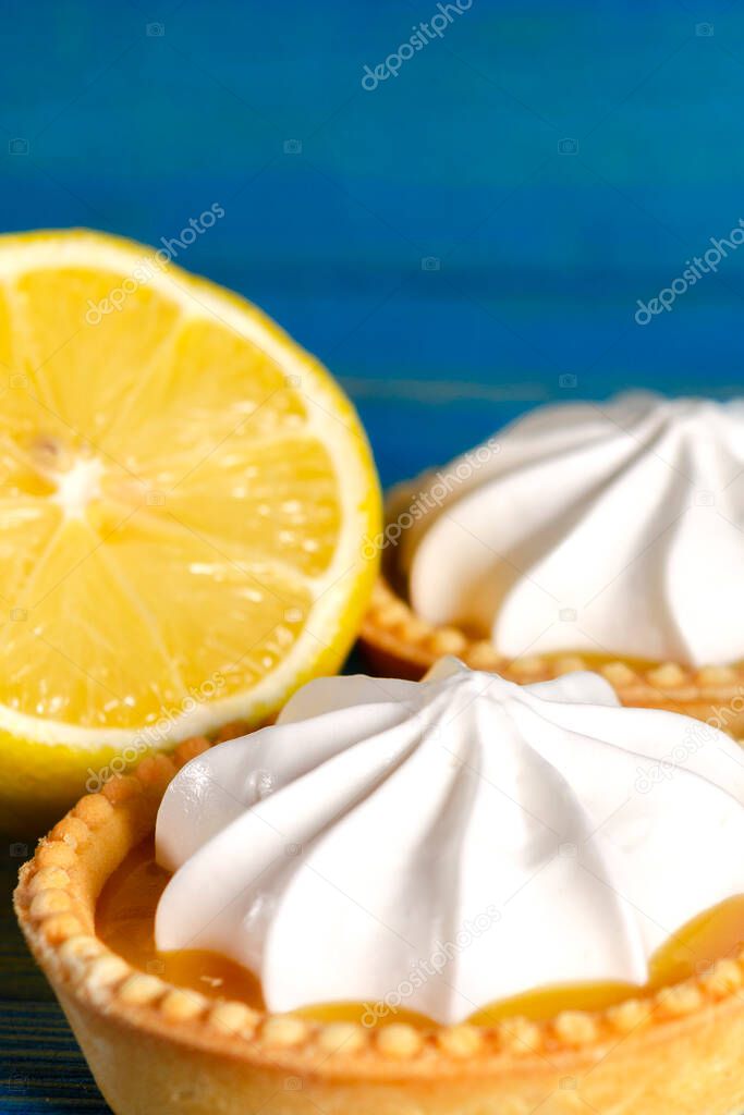 Lemon tartlets, Homemade shortbread mini tart cakes with lemon curd and whipped cream, blue background copy space